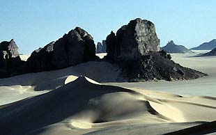 Dunkle Felskolosse, typisch für die Region um Djanet, ragen aus den Dünen des Erg Admer, Algerien