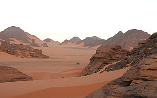 Abendstimmung im Akakus-Massiv. Felsen eingebettet in Sanddünen, Libyen