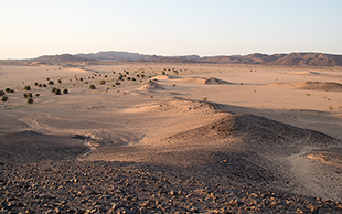 Heller Sand überzieht das dunkle Gestein der Hügel, Bayuda, Sudan